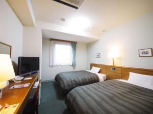 a hotel room with two beds and a television at Hotel Route-Inn Kani in Kani
