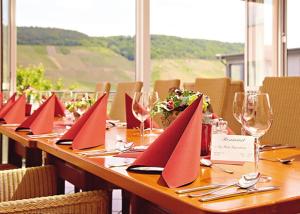a long wooden table with red napkins and wine glasses at WeinBergHotel Nalbach in Reil