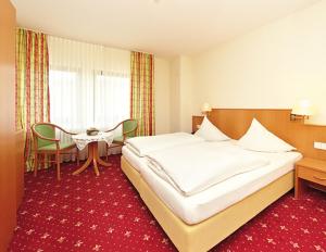 a hotel room with a large bed and a table at WeinBergHotel Nalbach in Reil
