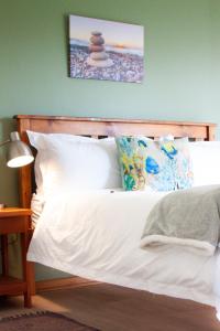 un letto con lenzuola e cuscini bianchi in una camera da letto di Swakop Strand Cottage Unit C a Swakopmund