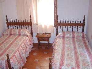 1 dormitorio con 2 camas, mesa y ventana en Mesón de Lagartera, en Lagartera