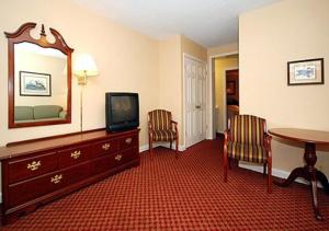 um quarto de hotel com televisão, mesa e cadeiras em Ambassador Inn em Fayetteville