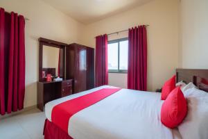 1 dormitorio con 1 cama grande y cortinas rojas en Al Reem Hotel Apartments, en Sharjah
