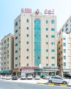 a large building with cars parked in a parking lot at Al Reem Hotel Apartments in Sharjah