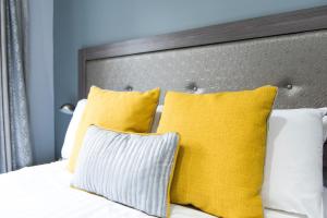 a bed with yellow and white pillows on it at Belmont Llandudno in Llandudno