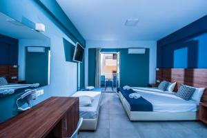a blue room with two beds and a table at Stalis Hotel in Stalís