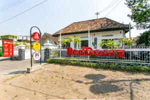 日惹RedDoorz Plus near Taman Sari 2的栅栏上带有红色标志的白色房子