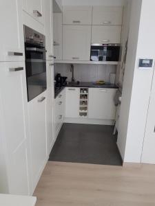 a white kitchen with white cabinets and a sink at Zeezucht in Koksijde