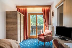 um quarto com uma televisão, uma cadeira e uma janela em Hotel Erna em Colle Isarco