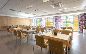 a dining room with tables and chairs and large windows at Aqua-Zdrój in Wałbrzych