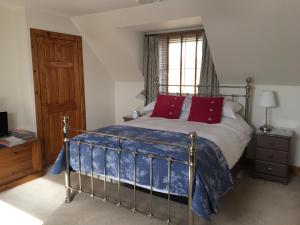 a bedroom with a bed with red pillows and a window at Off The Hill B&B in Isleornsay