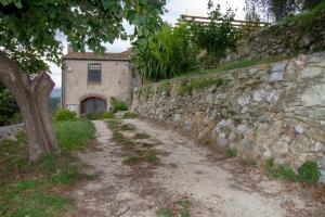 een stenen muur naast een onverharde weg met een gebouw bij Casa dei Templari in Finale Ligure