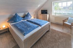 a bedroom with a bed with blue pillows at Nordsee-Nest in Ostochtersum