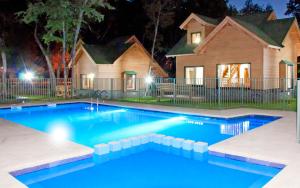 a swimming pool in front of a house at night at Complejo Turistico Los Hualles in Las Trancas
