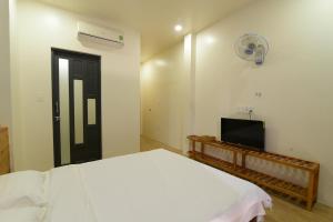 1 dormitorio con 1 cama blanca y TV en Gấu's House en Vung Tau