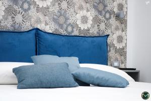 a bed with blue and white pillows and a wall at MARGHERITA BOUTIQUE ROOMS in Margherita di Savoia