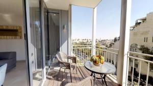 uma varanda com uma mesa e cadeiras. em Rental Israel-Mamila Residences 14 em Jerusalém