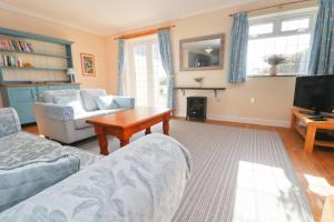 a living room with a couch and a tv at BY THE BEACH Harlyn Bay in St Merryn
