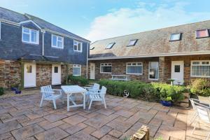 un patio con mesa y sillas y un edificio en BY THE BEACH Harlyn Bay en St Merryn