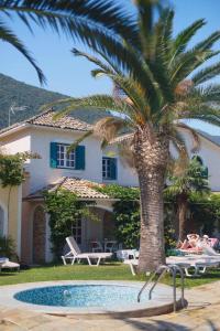a palm tree in front of a house with a pool at Valentino Corfu in Ýpsos