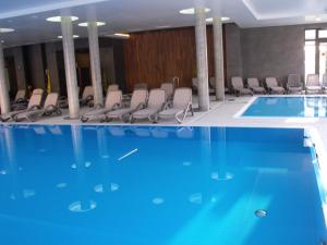 a large swimming pool with chairs in a building at Apartament Bałtyk Polanki Park in Kołobrzeg