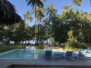 una piscina en el complejo con sillas y palmeras en Mahogany Resort & Spa en El Nido