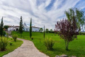 a path in a field with a house in the background at Hotel Rural Arroyo la Plata by Bossh Hotels in Jerez de los Caballeros