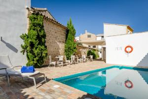 Una piscina en un patio con sillas y un edificio. en YIT La Casona del Arco, en Baeza