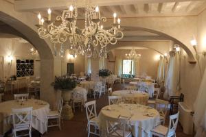 un comedor con mesas blancas y una lámpara de araña en Relais I Piastroni, en Monteverdi Marittimo