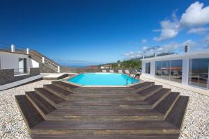 una piscina con escaleras de madera que conducen a una casa en 35th Atlantic View, en Lajes do Pico