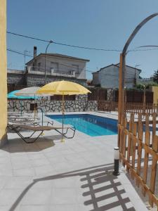 ein gelber Regenschirm und Stühle neben einem Pool in der Unterkunft Apartamentos "Casa Rural de Aldea" in Aldea del Fresno