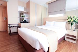 a bedroom with a large bed with white sheets at Petals Inn in Bangkok