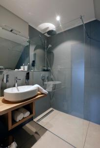 a bathroom with a sink and a glass shower at Patentkrug Design Hotel in Oldenburg