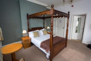 um quarto com uma cama de dossel e uma mesa de madeira em The Golf Hotel em Silloth