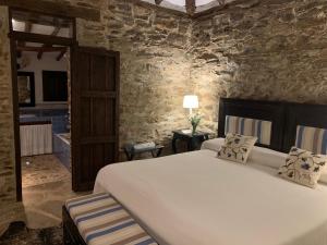 a bedroom with a large white bed and a stone wall at El Añadío in Vilches