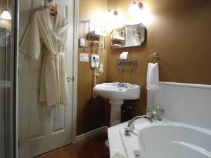 a bathroom with a tub, toilet, sink and mirror at The Beacon Inn at Sidney in Sidney