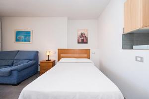 um quarto com uma cama e um sofá azul em MARSIN PLAYA 403 Vivienda Vacacional em Las Palmas de Gran Canárias