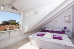 a bedroom with a bed with purple pillows and a window at Gugilly Old Town Haven in Dubrovnik