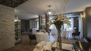 une salle à manger avec des tables et un vase de fleurs dans l'établissement Resort Limax Acis, à La Morra