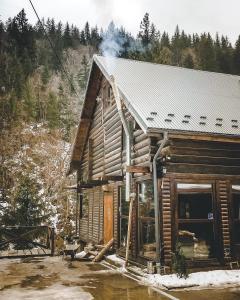 una cabaña de madera con humo saliendo de ella en 4 Mountains Hotel en Bystrets