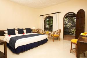 Neptune Paradise Beach Resort & Spa - All Inclusive في Galu: غرفة نوم بسرير وطاولة وكراسي