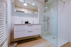 een witte badkamer met een wastafel en een douche bij Jef in Nieuwpoort
