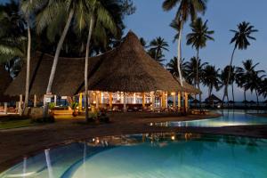 a resort with a thatched building and a swimming pool at Neptune Paradise Beach Resort & Spa - All Inclusive in Galu