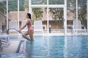 Una donna in bikini in piedi in piscina di Relais I Piastroni a Monteverdi Marittimo