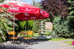 une table et des chaises sous un parapluie rouge à côté d'une fontaine dans l'établissement Zajazd Pod Gwiazdami, à Lublin