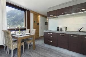 een keuken met een tafel, stoelen en een raam bij APARTMENT BEAUSITE - Alpes Travel - Central Chamonix - Sleeps 4 in Chamonix-Mont-Blanc