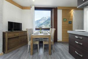 een keuken met een tafel met stoelen en een televisie bij APARTMENT BEAUSITE - Alpes Travel - Central Chamonix - Sleeps 4 in Chamonix-Mont-Blanc