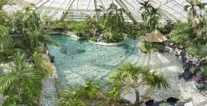 an indoor pool in a greenhouse with people in it at Center Parcs De Eemhof in Zeewolde