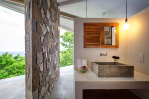 
a bathroom with a stone wall and a large window at Cocolia Hotel in Mazunte
