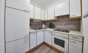 uma cozinha branca com armários brancos e um lavatório em Appartements Living Saalbach em Saalbach-Hinterglemm